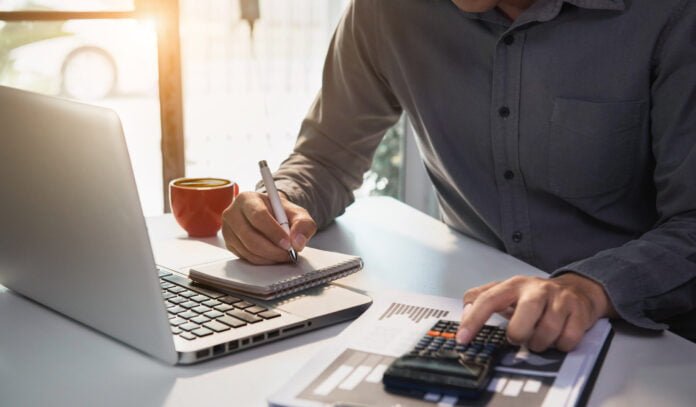Male businessman working on desk office with using a calculator to calculate the numbers, finance accounting concept.