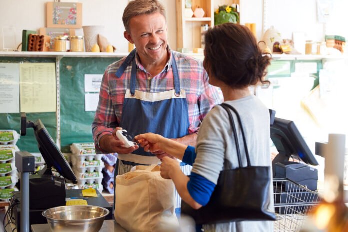 Customer At Checkout Of Organic Farm Shop Making Contactless Payment