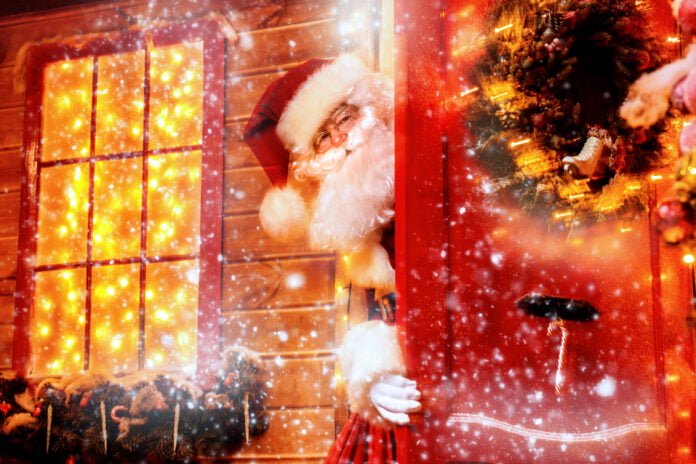 Santa Claus peeking out from behind festive door