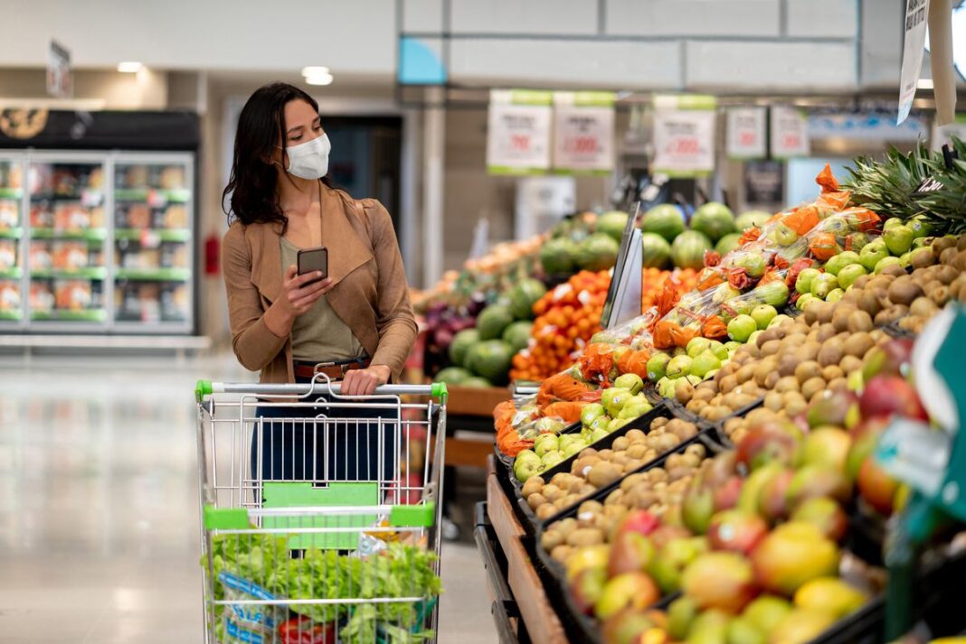 Woman grocery shops with face mask on during COVID-19 pandemic.