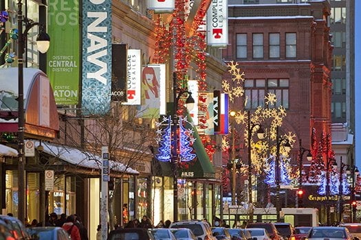 Sainte-Catherine Street storefronts adorned/aglow with Christmas lights