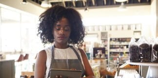 In the Age of AI, Investing in the Human Touch Is Fundamental for Retailers Retail worker using smart device