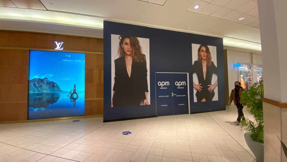 "Opening Soon" signage for APM Monaco on lower level of CF Chinook Centre