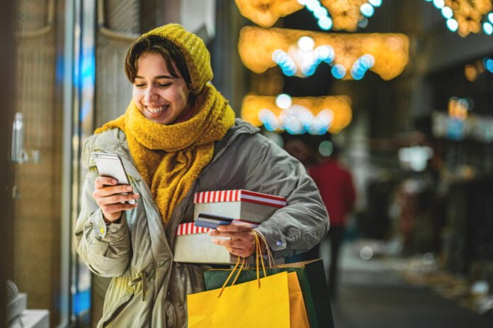 Young woman with Christmas presents using mobile banking
