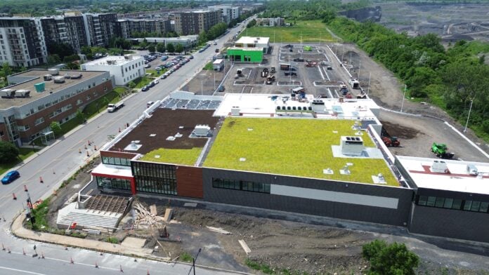 Aerial view of the new commercial development Faubourg Contrecœur in Montréal’s Mercier–Hochelaga-Maisonneuve borough. With the addition of Dollarama and McDonald's alongside anchor tenant IGA, the retail centre has now reached full occupancy ahead of its planned summer 2026 opening.